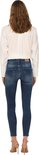 Vrouw van achteren gezien, in een donkerblauwe skinny jeans met rafelige zoom en een wit shirt.