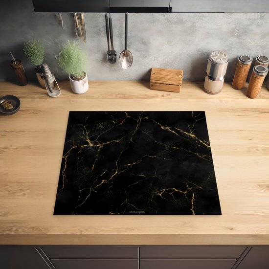 Zwarte inductiebeschermer met marmerprint en gouden accenten, geplaatst op een houten aanrechtblad.