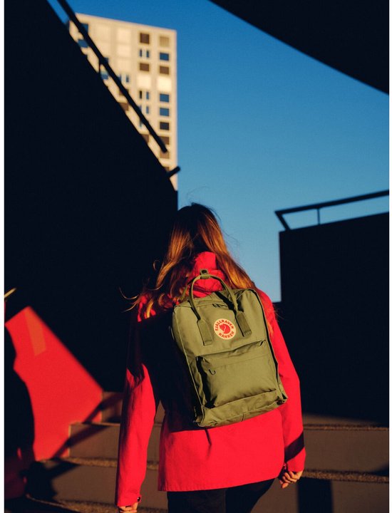Groene Fjällräven Kånken rugzak gedragen door een vrouw die een trap oploopt.