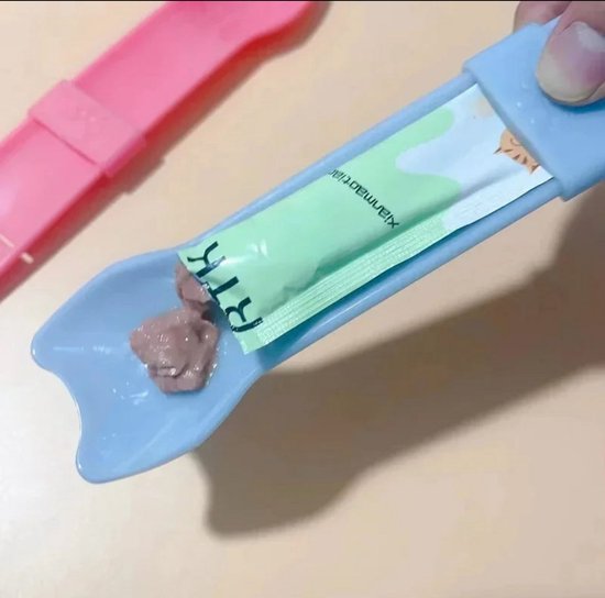 Close-up van een blauwe lepel met "RTK" verpakking en kattenvoer, naast een roze lepel.