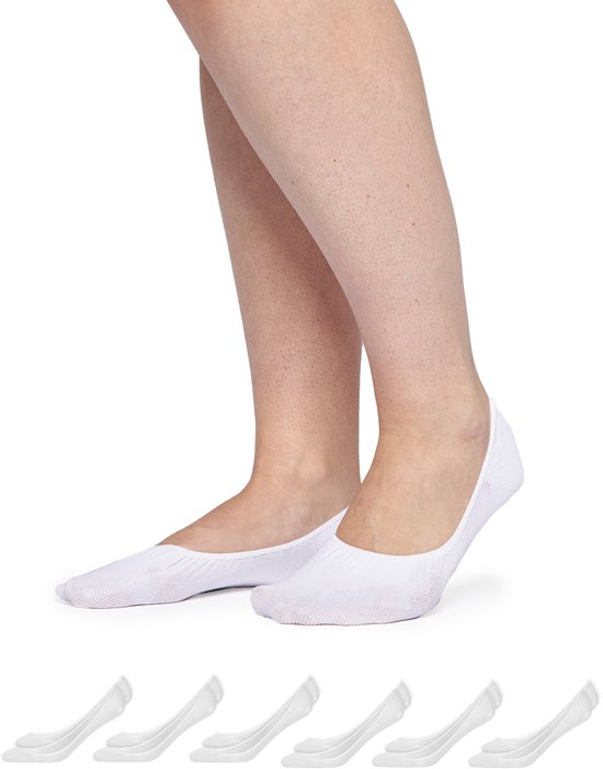 Voeten van een vrouw die witte onzichtbare sokken draagt, met een rij van vijf sokken eronder.
