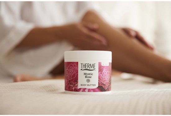 Therme Mystic Rose body butter pot naast een vrouw die haar benen insmeert.