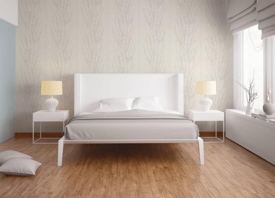 Een wit bed met grijze lakens staat op een houten vloer voor een muur met verticaal bloesemdessin.
