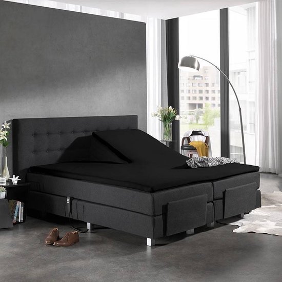 Een verstelbaar zwart bed met een gedraaid hoeslaken en een deken.