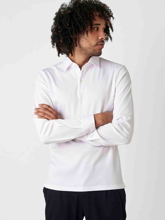 Man met gekruiste armen in wit longsleeve poloshirt en donkerblauwe broek.