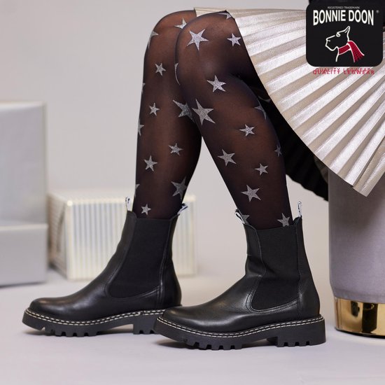 Model met zwarte panty met zilveren sterren en zwarte laarzen.