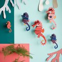 Een decoratieve muur van papieren zeepaardjes in blauw, roze en rood.
