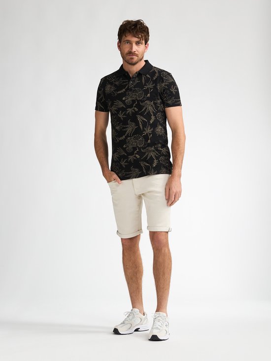 Man met beige broek en zwart shirt met bloemenprint.