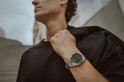 Een man met zwarte kleding draagt een Edifice horloge met groene wijzerplaat om zijn linkerpols.