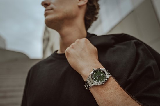 Een man met zwarte kleding draagt een Edifice horloge met groene wijzerplaat om zijn linkerpols.
