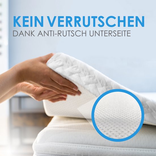 Mains montrant le dessous antidérapant d'un surmatelas blanc à picots.