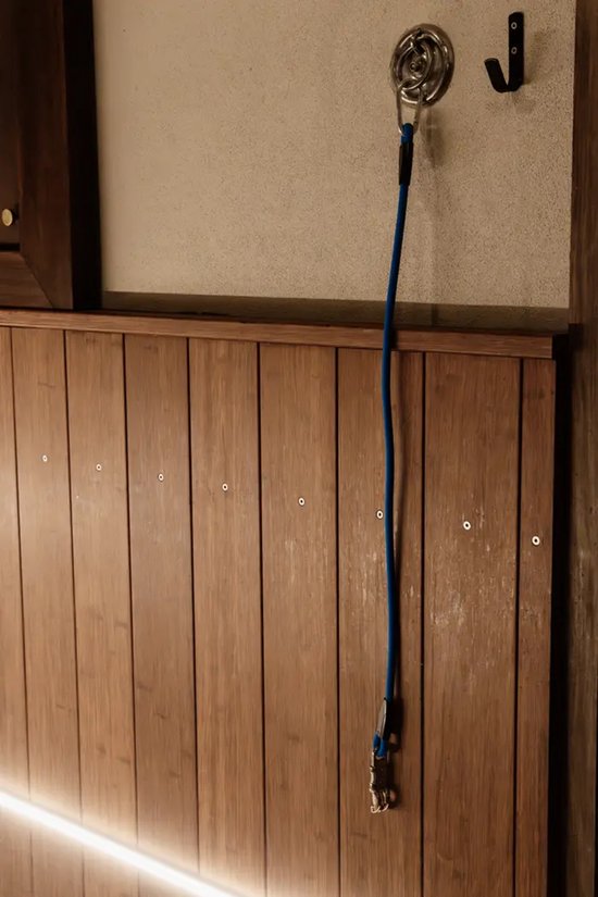 Blauwe siliconen trailerlijn, opgehangen aan een muurhaak.