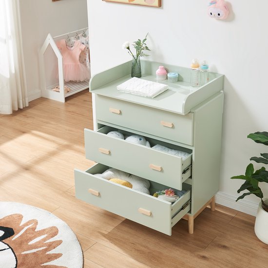 Mintgroene commode met open lade, gevuld met babyartikelen, in een kinderkamer.