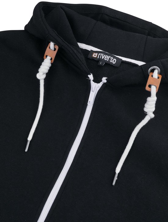 Detail van de sluiting van een zwarte hoodie met rits, koordjes en label.