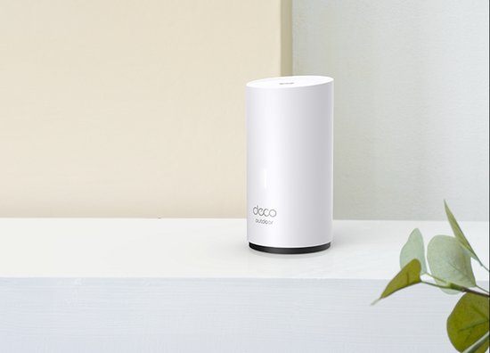Witte Deco X50 Outdoor mesh wifi-unit op een witte plank met een plant ernaast.