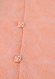 Close-up van twee koperkleurige knopen op een perzikkleurige kanten blouse.