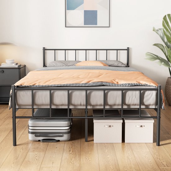 Cadre de lit noir en métal avec tête de lit, avec draps rayés et couverture orange, et espace de rangement sous le lit.