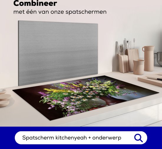 Een inductiebeschermer met een boeket bloemen, staande op een aanrecht naast een grijze spatscherm.