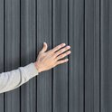 Hand raakt de verticale, grijze, kunststof panelen van een berging aan.