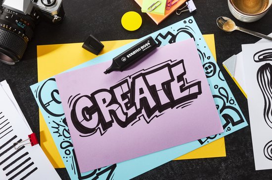 Een Stabilo Boss Original marker ligt op een paars vel papier met het woord 'CREATE' erop getekend in zwart.