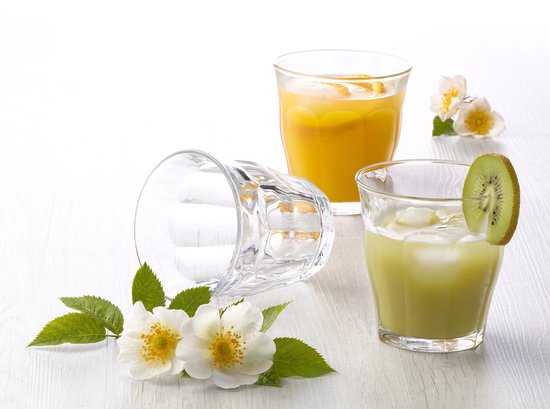 Deux verres, l'un avec un cocktail au kiwi et une tranche de kiwi, l'autre avec du jus d'orange et des tranches d'orange, avec des fleurs blanches.