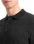 Detail van een man in een zwart poloshirt met geborduurd logo op de borst.