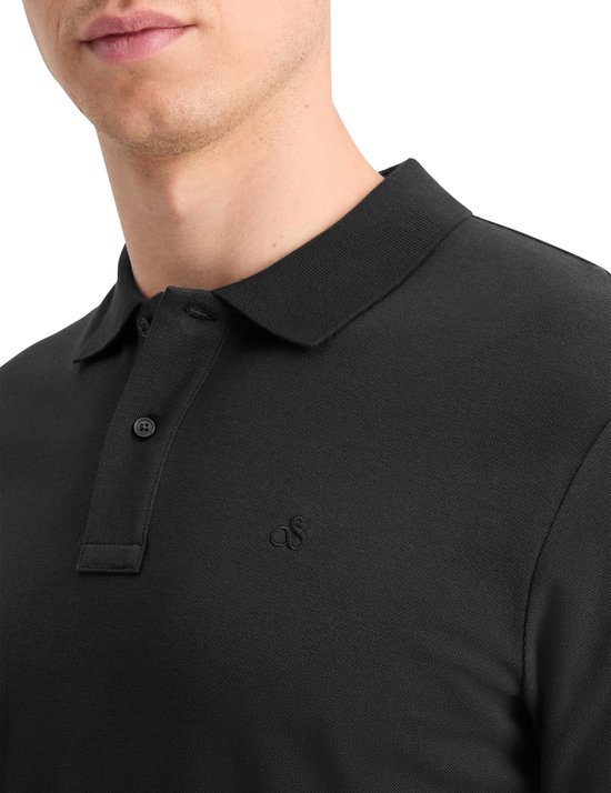 Detail van een man in een zwart poloshirt met geborduurd logo op de borst.