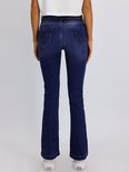 Achterkant van een donkerblauwe flared jeans met wijde pijpen en witte sneakers.