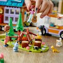 LEGO Friends-figuren kamperen met een vuur, een katje, een konijn en een gele puppy, naast een camper en een huisje.