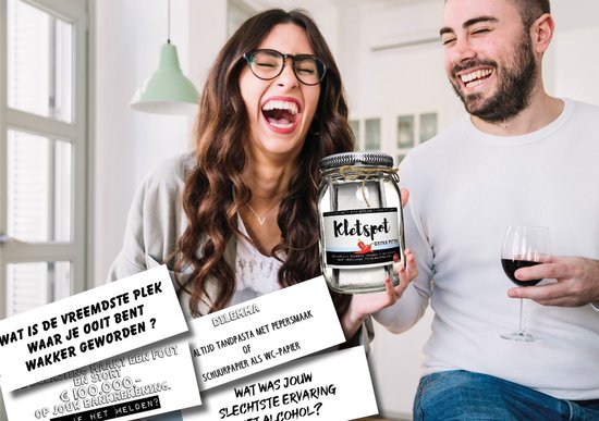 Man en vrouw lachen, terwijl de man een glazen pot 'Kletspot EXTRA PITTIG' vasthoudt met kaartjes.