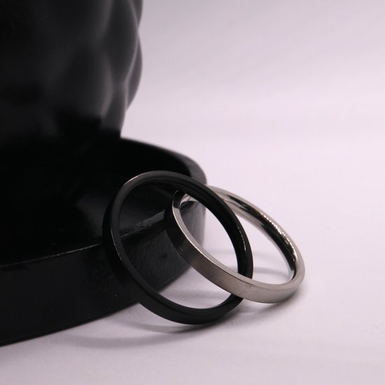 Zilverkleurige en zwart matte ringen die naast een zwarte schaal in elkaar grijpen.
