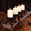 Rustieke houten schaal gevuld met koperbruine kerstballen, versierd met vier brandende witte kaarsen in zwarte houders.