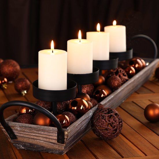 Rustieke houten schaal gevuld met koperbruine kerstballen, versierd met vier brandende witte kaarsen in zwarte houders.