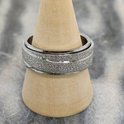 Zilverkleurige ring met een glinsterende, gestreepte band in het midden, op een houten standaard.