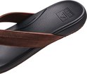 Detail van een bruine Reef slipper met zwart gestippeld voetbed, Reef logo en tekst 'ANATOMIC CONTOURING'.