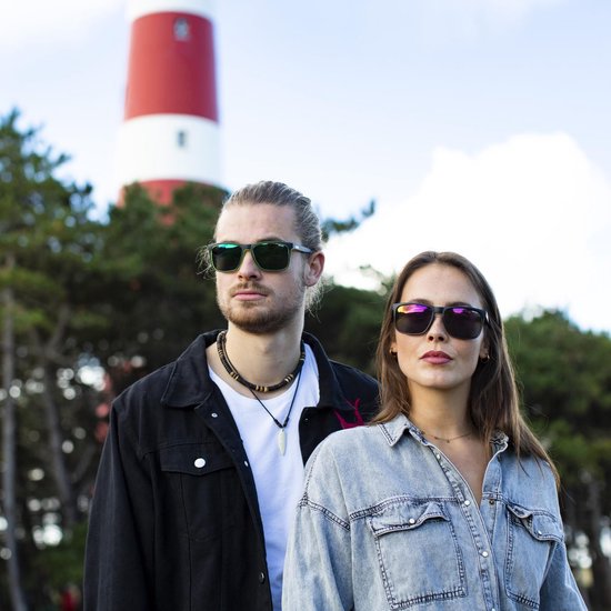 Man en vrouw met zonnebril bij een vuurtoren.
