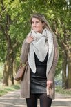 Vrouw met een off-white gebreide driehoekssjaal, gedragen met een bruine vest en zwarte leren rok.