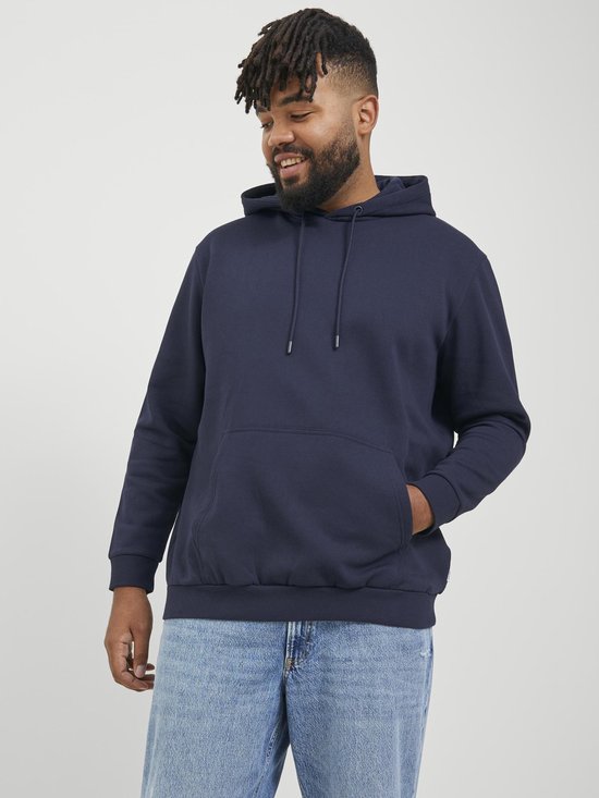 Man met een brede glimlach in een donkerblauwe hoodie en jeans.