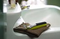 Groene en zwarte Philips OneBlade trimmer ligt op een bruine handdoek bij een wasbak.