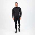 Man in zwart fietsjack en fietsbroek met logo's, lacht.