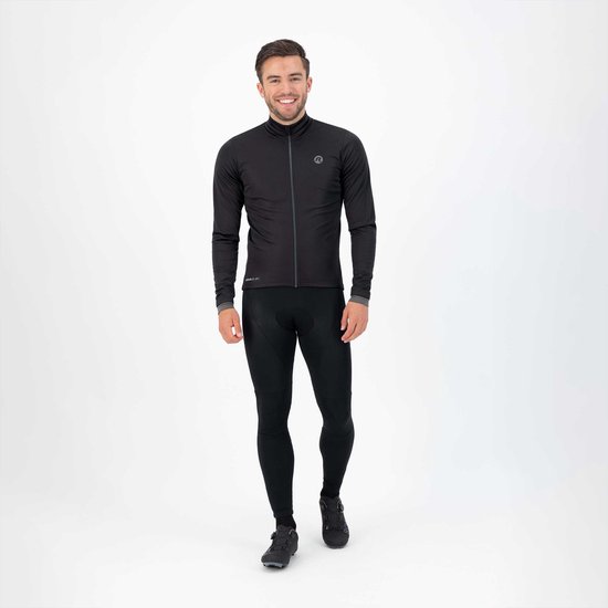 Man in zwart fietsjack en fietsbroek met logo's, lacht.
