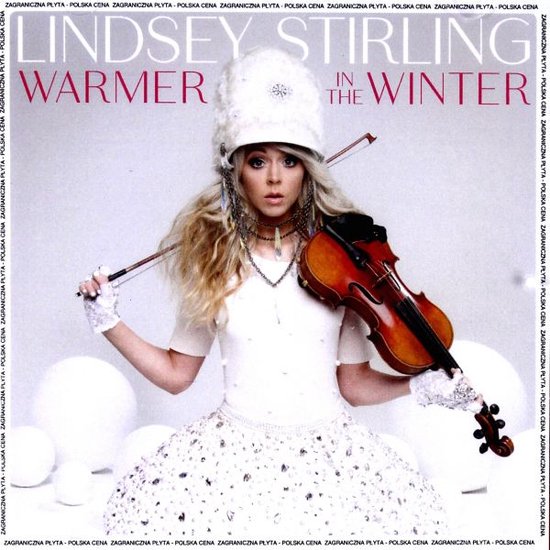 Lindsey Stirling met viool, draagt een witte jurk en een witte muts met versieringen.