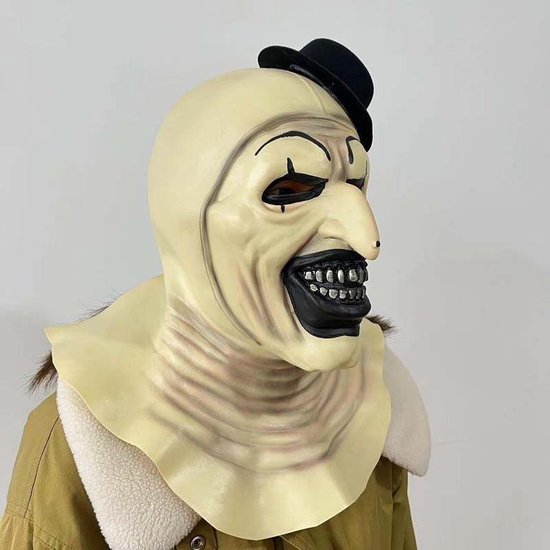 Creatie van 'Art the Clown' masker met opvallende gele huid, grote zwarte mond, tanden, oogmake-up en een zwarte hoed.