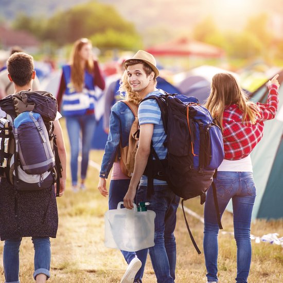 Een groep kampeerders loopt over een veld, een man draagt een opvouwbare jerrycan.