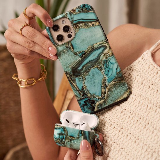 Telefoonhoes en AirPods-hoes in groen en goud marmerpatroon, in handen van een vrouw met gouden sieraden.