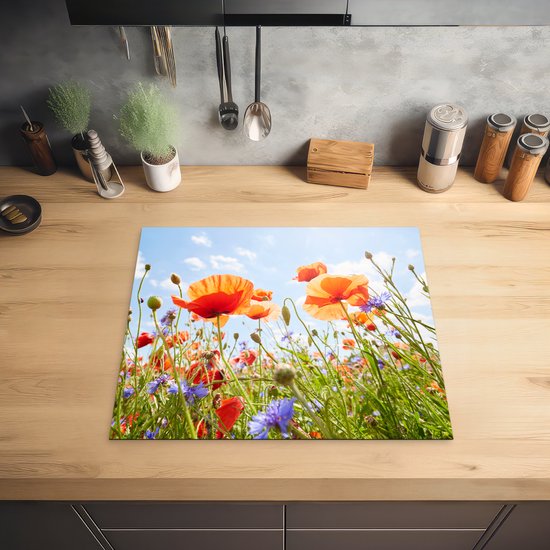 Een inductiebeschermer met een veld vol klaprozen en korenbloemen, op een houten aanrecht.