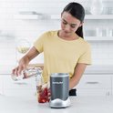 Vrouw met gele trui maakt een smoothie met de Nutribullet blender.