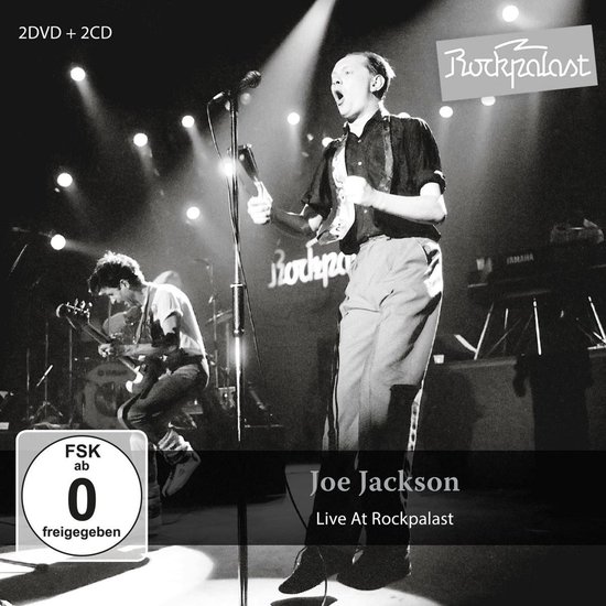 Joe Jackson live op het podium, zingend in een microfoon, met gitarist op de achtergrond. 'Rockpalast' logo bovenaan.