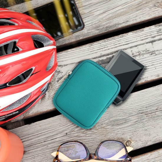 Petrol hoesje voor e-bike display, naast een rode fietshelm en een smartphone op houten ondergrond.