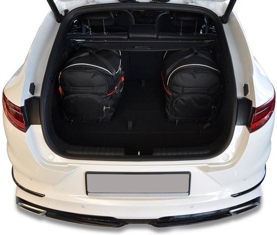 Twee zwarte reistassen met witte en rode accenten in de kofferbak van een witte auto.